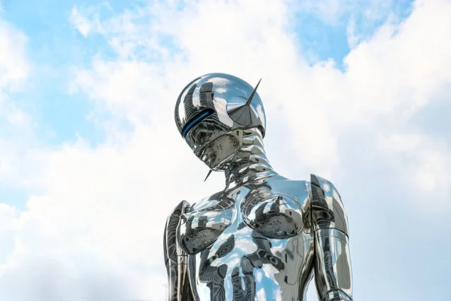 chrome robotic figure against blue sky, symbolizing AI and automation