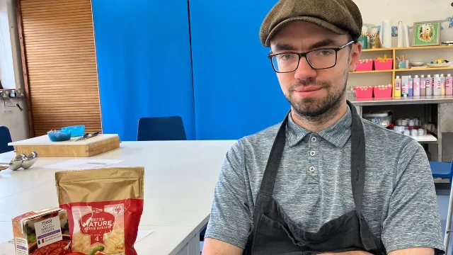 Kieran sits at a cooking table with ingredients