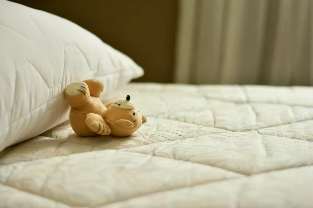 A softly lit bed with pillows and a small stuffed toy
