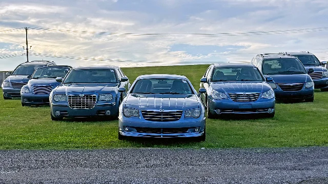 A lineup of blue Chrysler vehicles from 2007 parked in a row on a grassy field