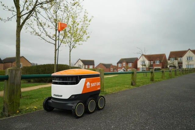 印有 Just Eat 标志的 Starship 配送机器人行驶在英国住宅区人行道上
