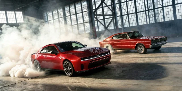 Two generations of Dodge Charger doing burnouts indoors
