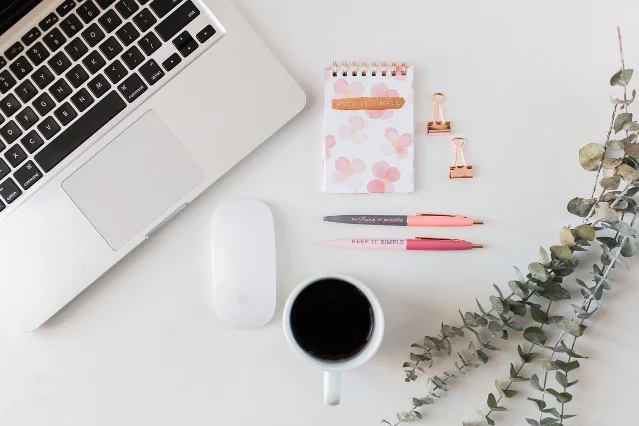 Laptop, phone, notebook, and coffee on a desk
