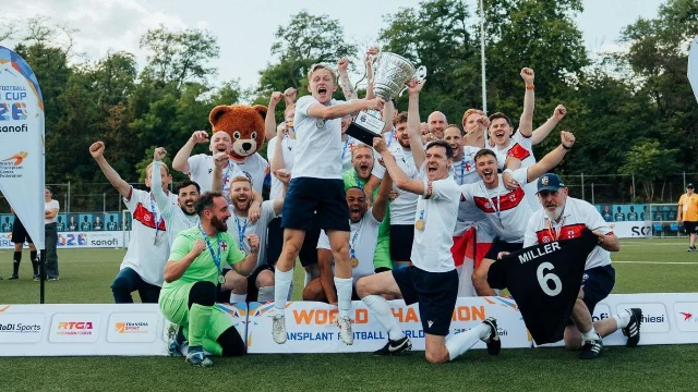 England's transplant football squad holding the Transplant Football World Cup trophy on the pitch in Frankfurt
