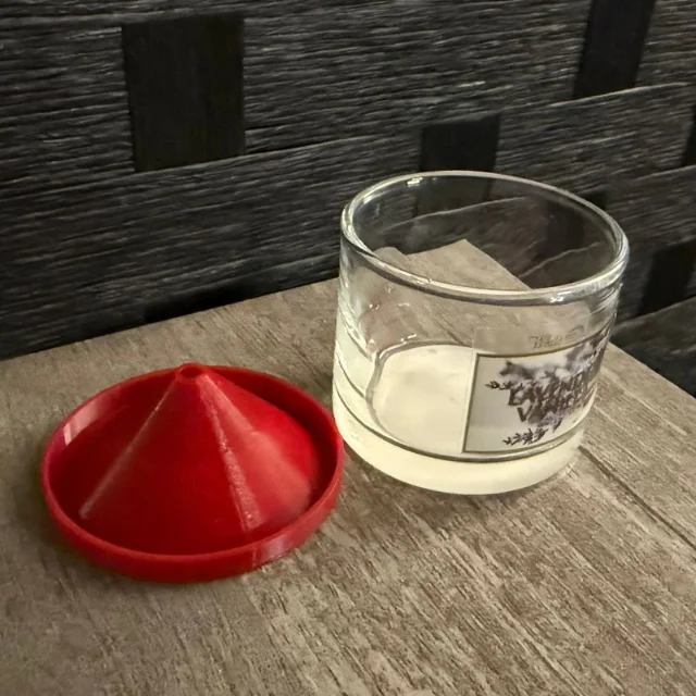 A red printed fruit-fly-trap lid beside a used mini candle jar