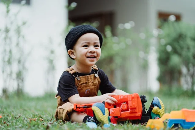 A smiling toddler playing outdoors with colorful toys — the SDQ measures emotional and behavioral functioning in children around this age