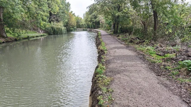 water beside a gravel towpath with trees along both sides