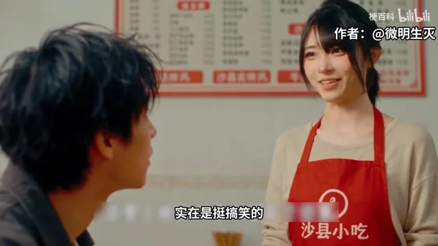 原片引用的真人短剧画面：沙县小吃店里，一位头发盘起的年轻女子穿米色上衣、系红色围裙，围裙上印着沙县小吃标志，笑着看向坐在对面的男顾客，背后墙上贴着红色价目表
