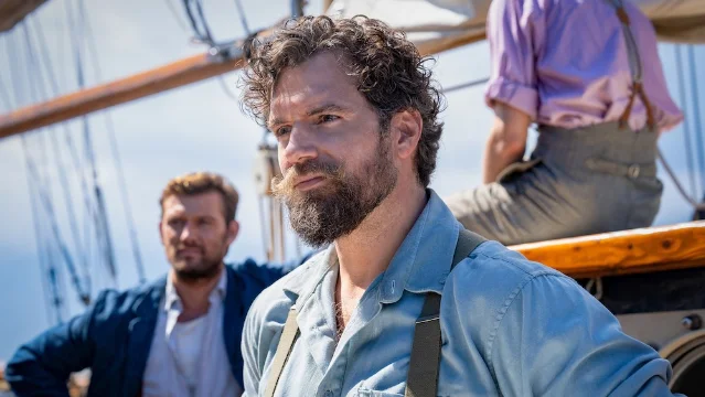 Henry Cavill as Gus March-Phillips standing on the deck of a boat with crew members in The Ministry of Ungentlemanly Warfare