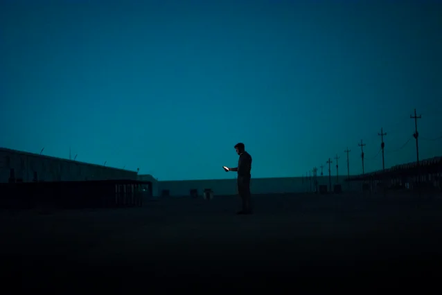 Solitary figure illuminated by a phone screen at night