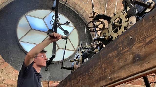 Matthew Buller turning the crank of the clock mechanism inside the tower at Ripon Grammar School