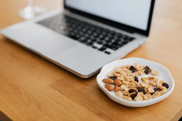 Mixed nuts next to a laptop on a wooden desk — a classic desk-ready strategic snack