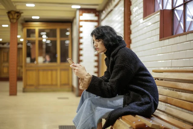 Young woman sitting alone, texting on a smartphone indoors
