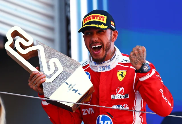Lewis Hamilton celebrates on the podium with his first-place trophy after winning his maiden Grand Prix for Ferrari at Barcelona 2026