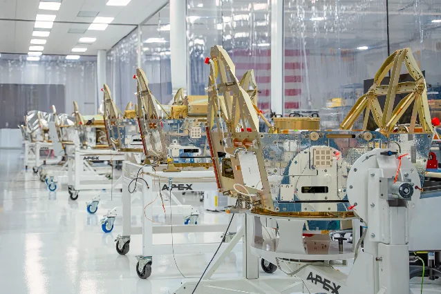 Apex Factory One 厂房内,多个卫星平台位于装配工位和移动支架上