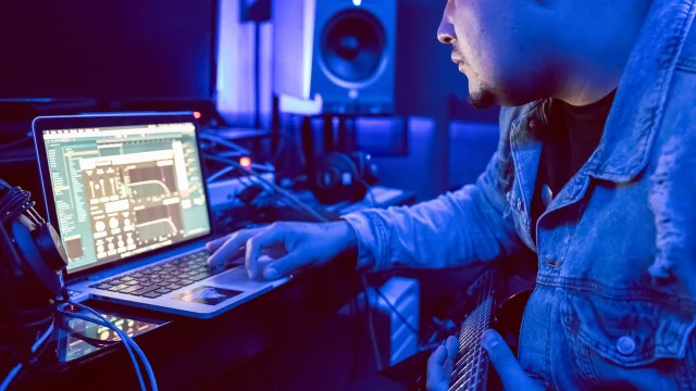音乐制作人在录音室使用笔记本电脑创作