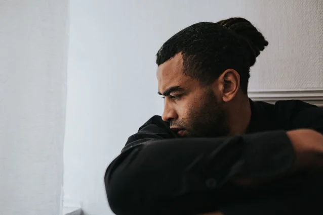 Young man sitting alone in deep thought, looking contemplative