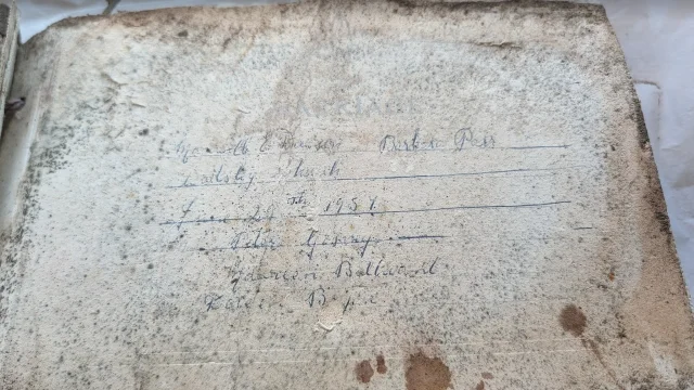 a water-stained page inside the album with a faint handwritten list in fountain pen
