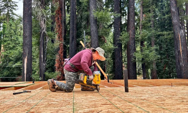 A volunteer uses a nail gun on the frame of Tonia Weakland's home in the Santa Cruz redwoods.