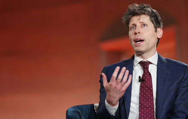 OpenAI CEO Sam Altman in a blue checked suit, speaking at an event