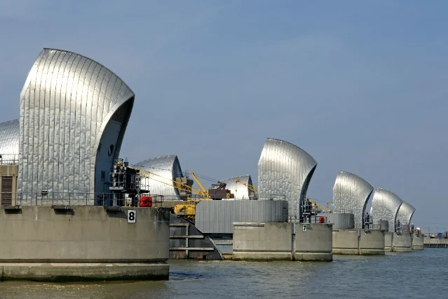 The Thames Barrier's silver gates and concrete piers viewed along the river