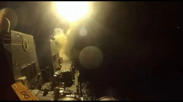 Nighttime naval vessel launching a missile with large flame and smoke at the launch port