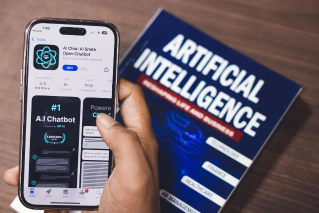 手持 iPhone 展示 AI App,旁放 Artificial Intelligence 书籍