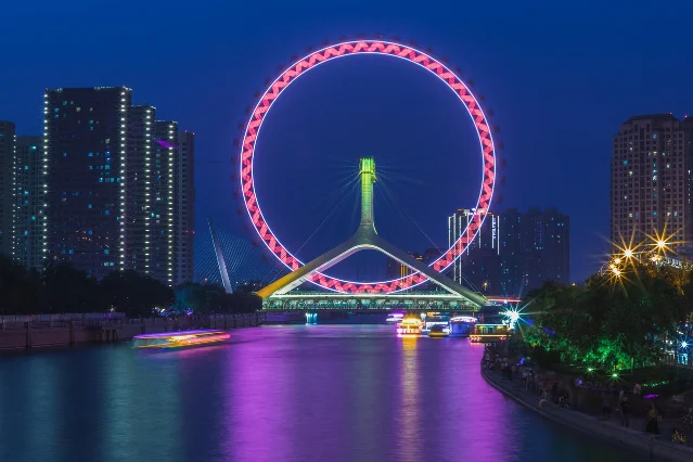 天津之眼摩天轮夜景,建于海河上,两侧是灯火通明的城市轮廓