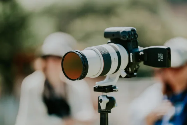 Professional white telephoto lens on tripod at an outdoor event