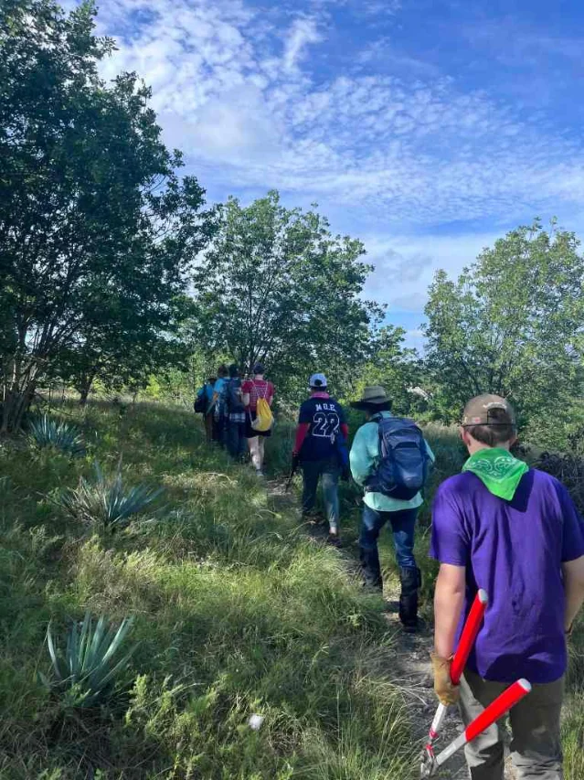 Volunteers walk through Oakmont Park's prairie restoration area with hand tools.