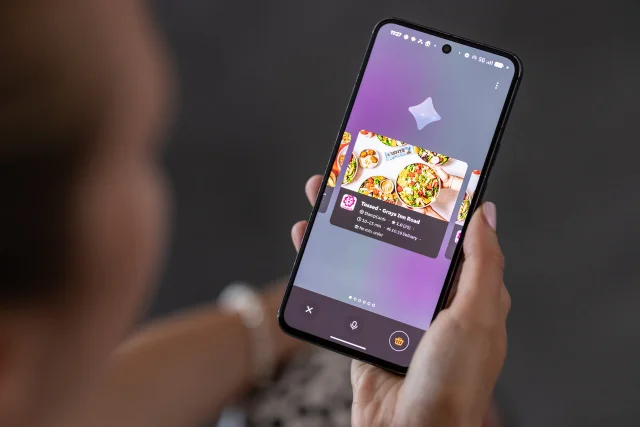 Just Eat 官方照片:用户手持手机查看带有餐厅卡片的点餐界面