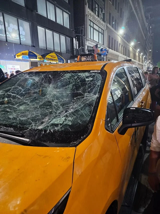 A smashed yellow taxi windshield at night in New York