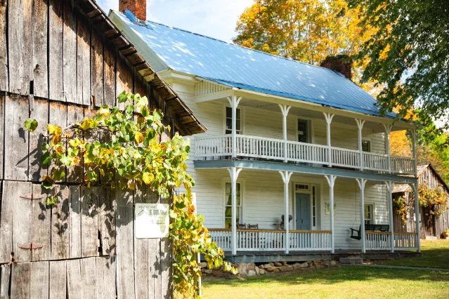 The Settlers Museum farmhouse seen from beside a weathered wooden outbuilding