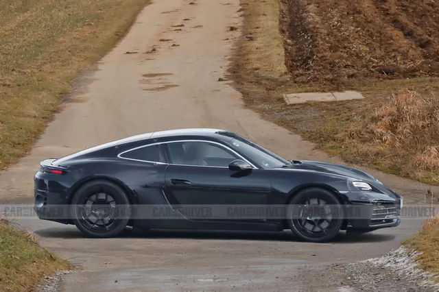 A black prototype of the electric Porsche 718 Cayman cornering on a dirt road, photographed by Car and Driver