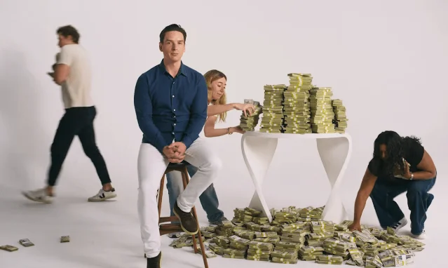 A staged pile of cash around a table in a white studio