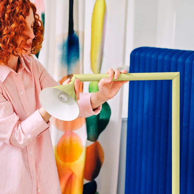 Person rotating yellow IKEA PS 2026 floor lamp, changing from uplighter to reading light to spotlight position