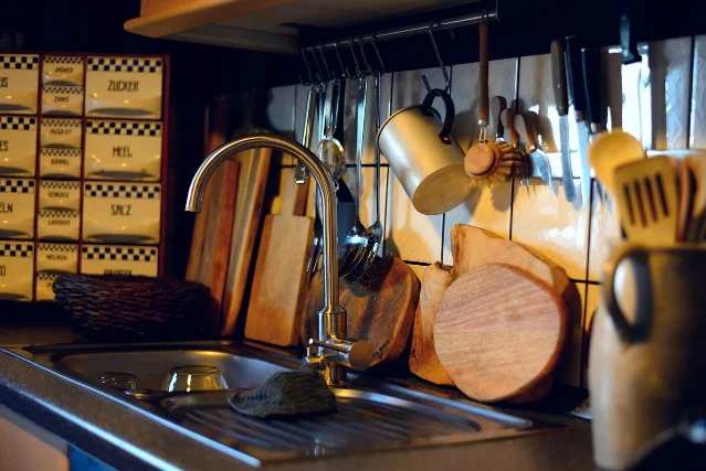 Wooden cutting boards propped beside a kitchen sink