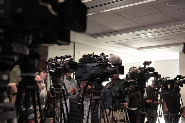 Cameras and reporters at a press conference media scrum