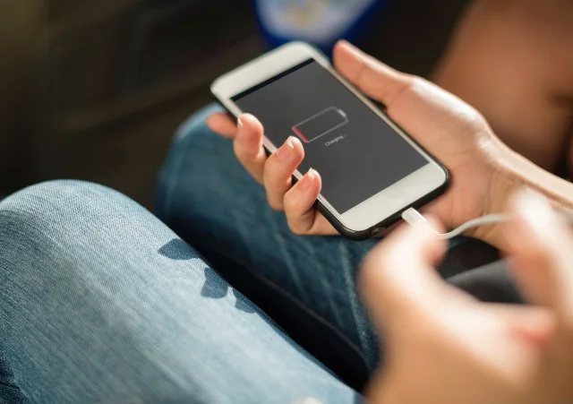 A smartphone with a low battery icon connected to a charging cable