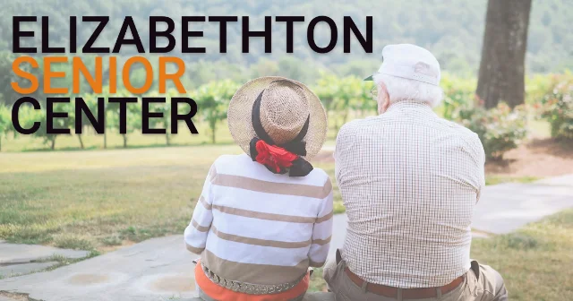 Two older adults sit outdoors on a path in a photo used by the Elizabethton Senior Center.