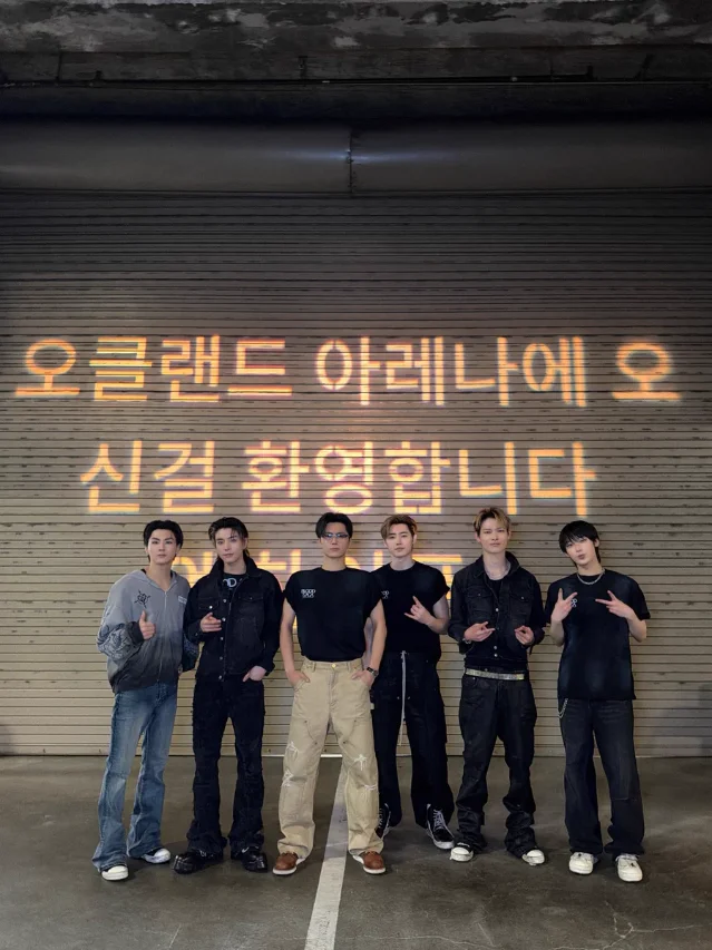 ENHYPEN 成员在 Oakland Arena 欢迎背景前的合照