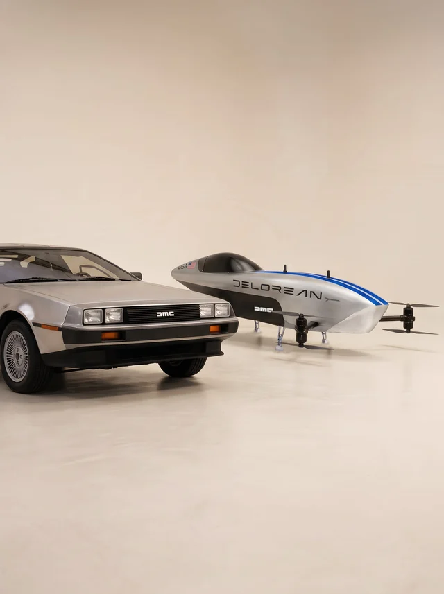 A silver DeLorean DMC-12 parked beside a sleek electric racing aircraft with DeLorean branding on a plain studio floor
