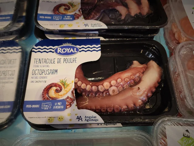 Supermarket package labeled TENTACULE DE POULPE and OCTOPUSARM with cooked octopus arm visible