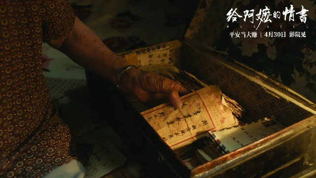 电影《给阿嬷的情书》剧照,阿嬷从旧木箱中取出侨批信封,碎花衣,旧木桌,光线昏黄