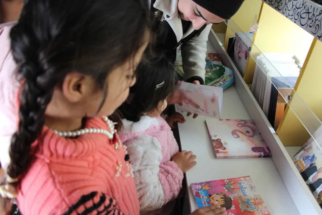 Children browse books inside the Mobile Cultural Bus.