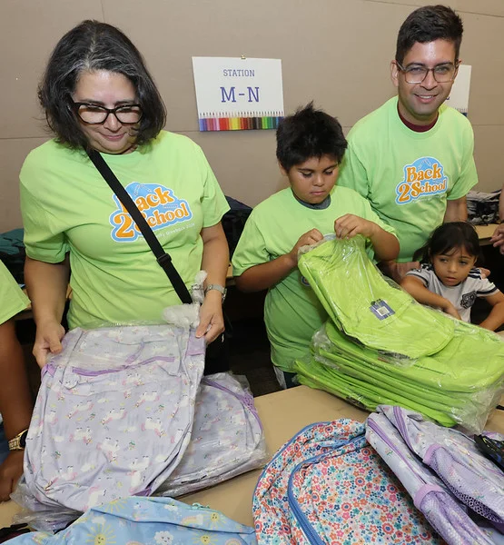 Children and adults move through a busy distribution area during the Back to School Community Giveback.