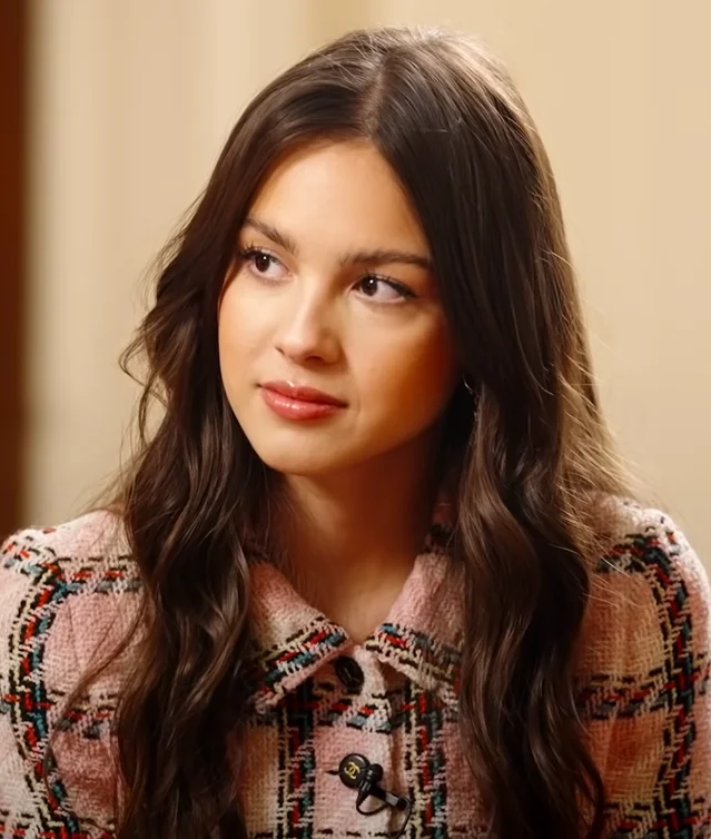 Olivia Rodrigo in a pink patterned top, looking off camera