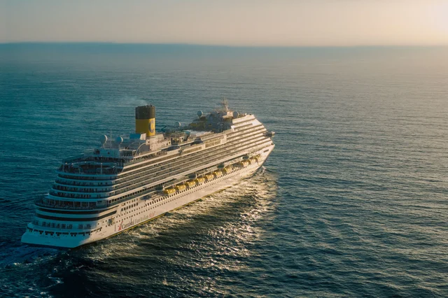 Cruise ship sailing at sunset on open ocean