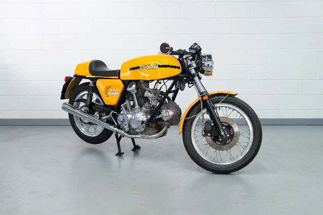 A yellow 1975 Ducati 750 Sport motorcycle photographed against a plain background