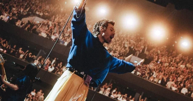 Harry Styles performing in front of a stadium crowd